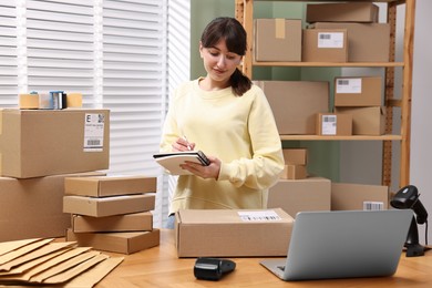 Photo of Parcel packing. Post office worker writing notes indoors