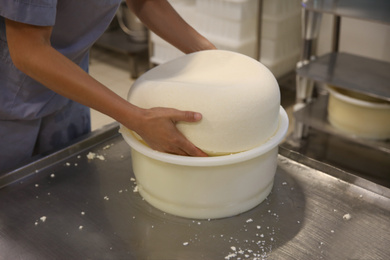 Photo of Worker taking fresh cheese from mould at modern factory, closeup