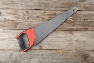Photo of Saw with colorful handle on wooden background, top view