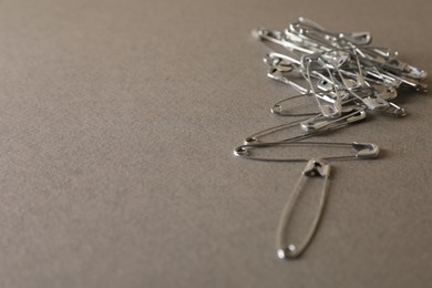Photo of Safety pins on grey textured background, closeup. Space for text