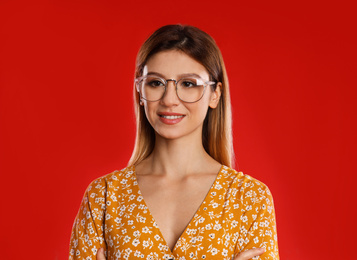 Portrait of young woman with glasses on red background