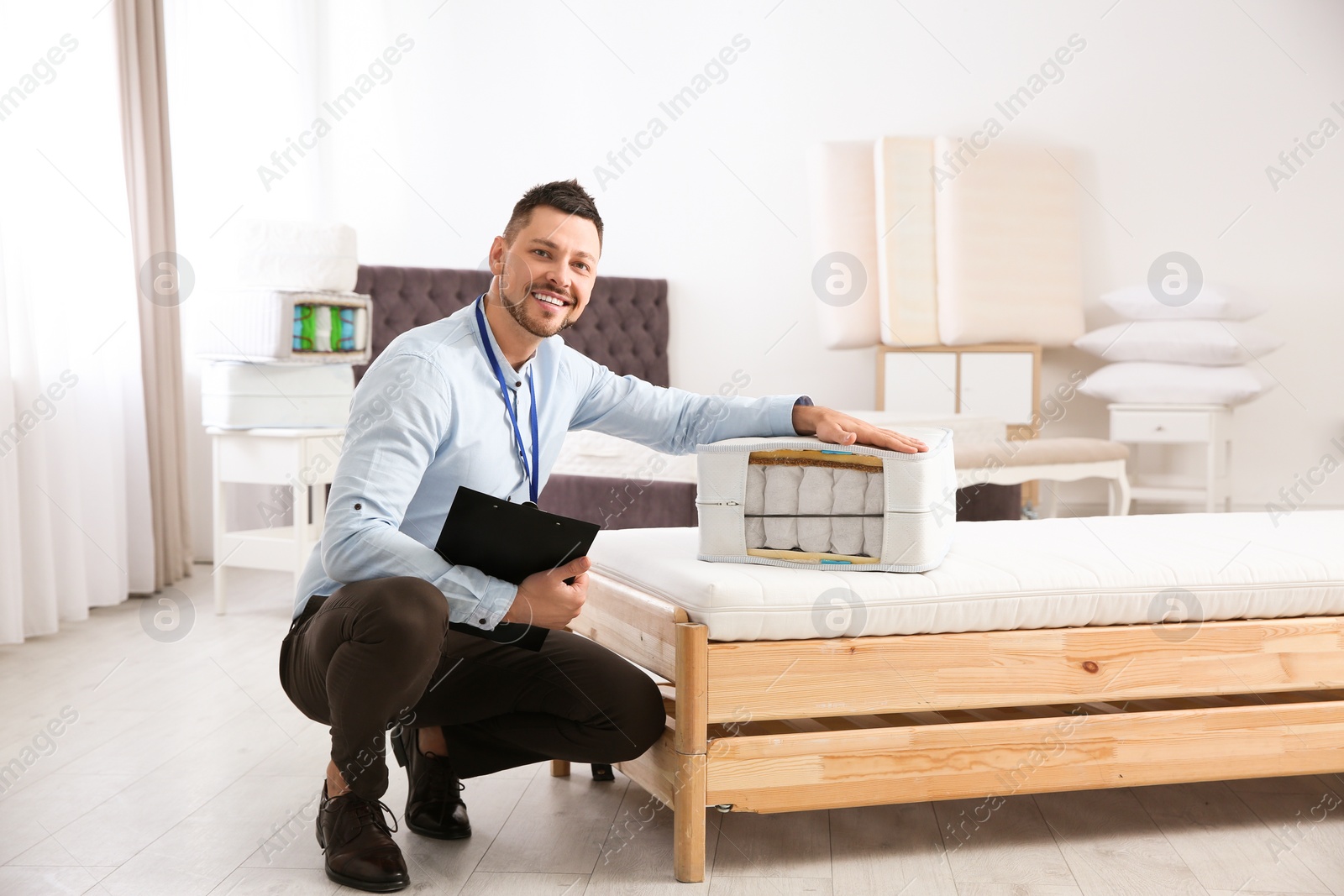 Photo of Salesman with section of mattress in furniture store