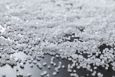 Photo of Scattered natural salt on black table, closeup