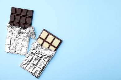 Photo of Tasty chocolate bars on light blue background, flat lay. Space for text