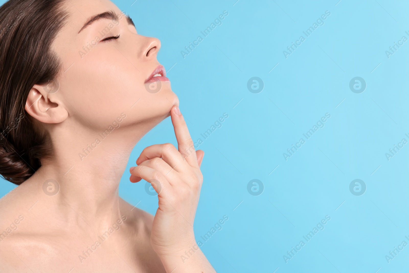 Photo of Young woman massaging her face on turquoise background. Space for text