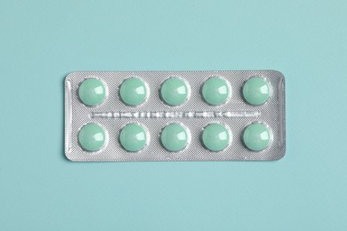 Photo of Pills in blister on turquoise background, top view