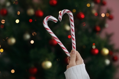 Photo of Woman holding candy canes on blurred background, closeup