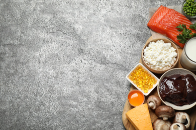 Flat lay composition with products rich in vitamin D on grey table. Space for text