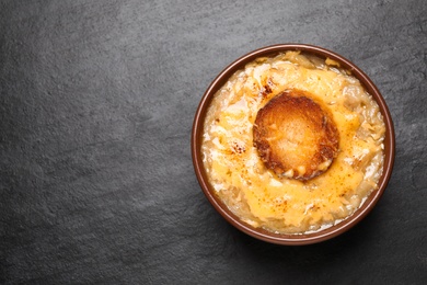 Tasty homemade french onion soup on black table, top view. Space for text