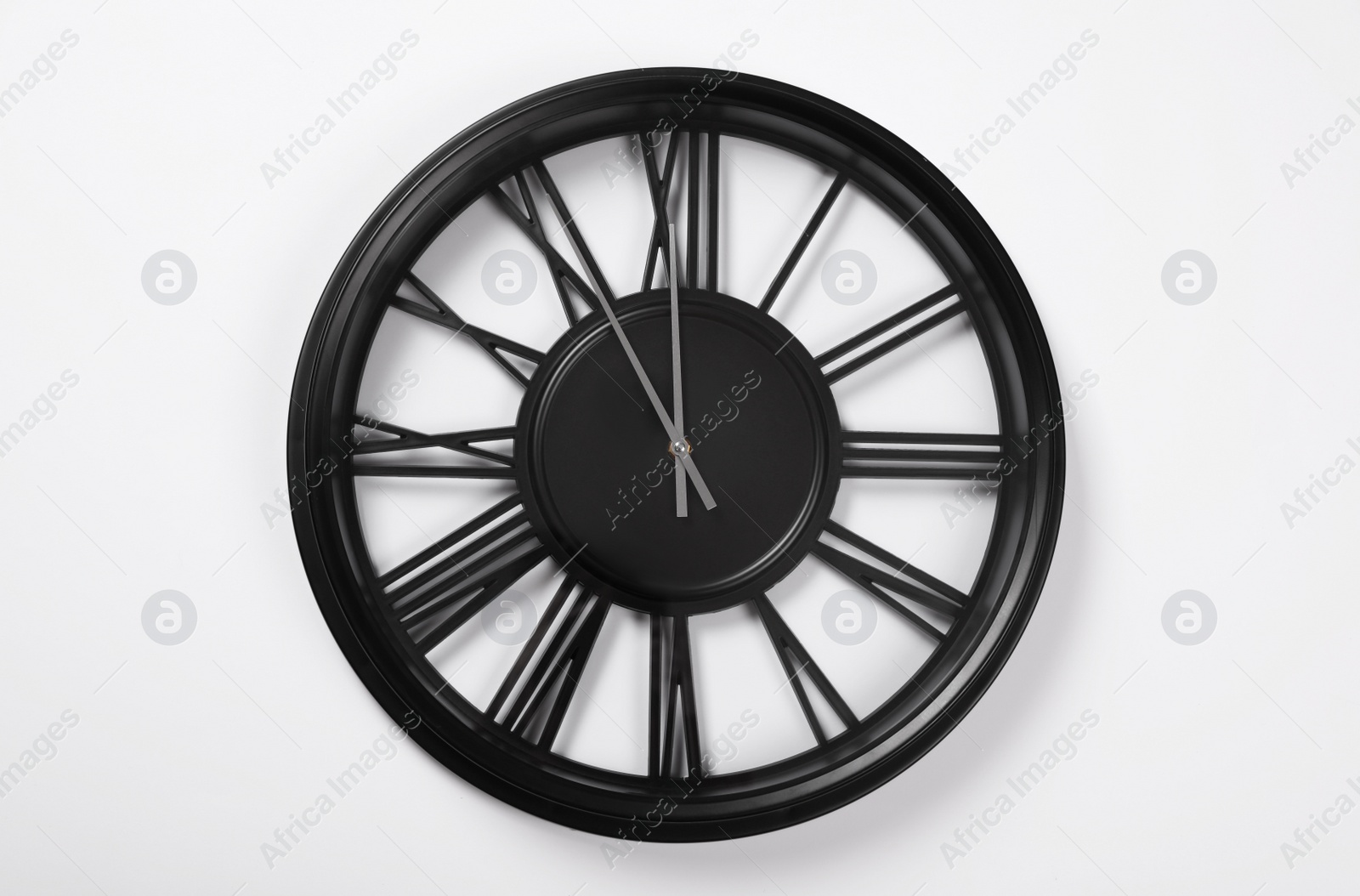 Photo of Stylish analog clock hanging on white wall. New Year countdown