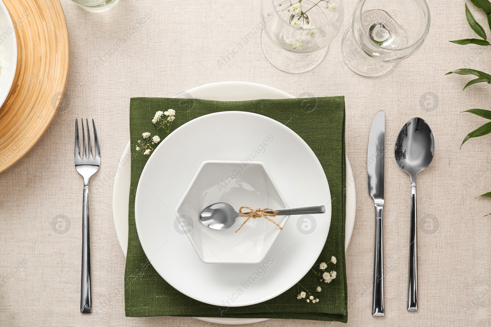 Photo of Elegant table setting with green plants on light cloth, flat lay