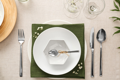 Elegant table setting with green plants on light cloth, flat lay