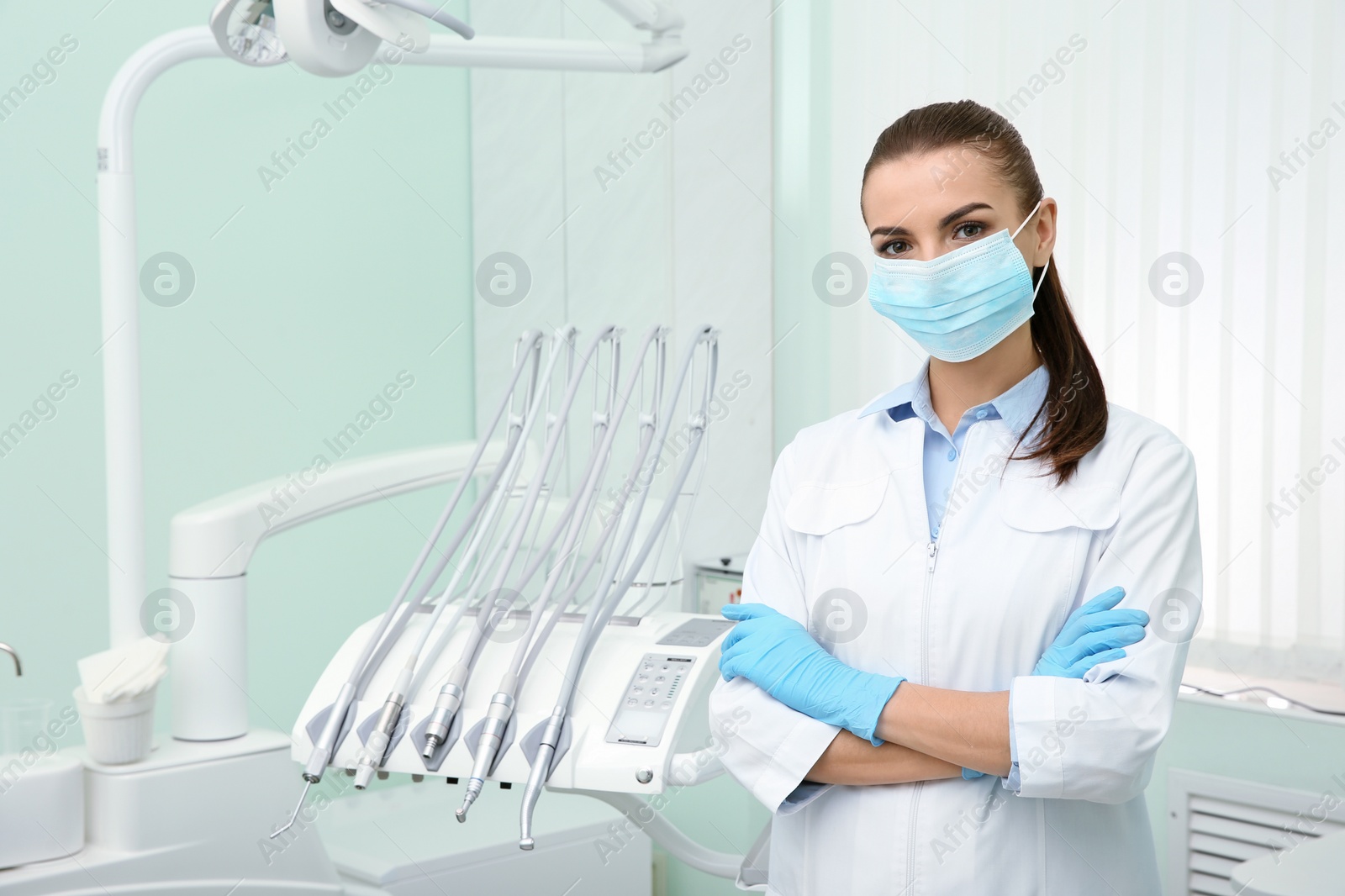 Photo of Young female dentist in white coat at workplace. Space for text