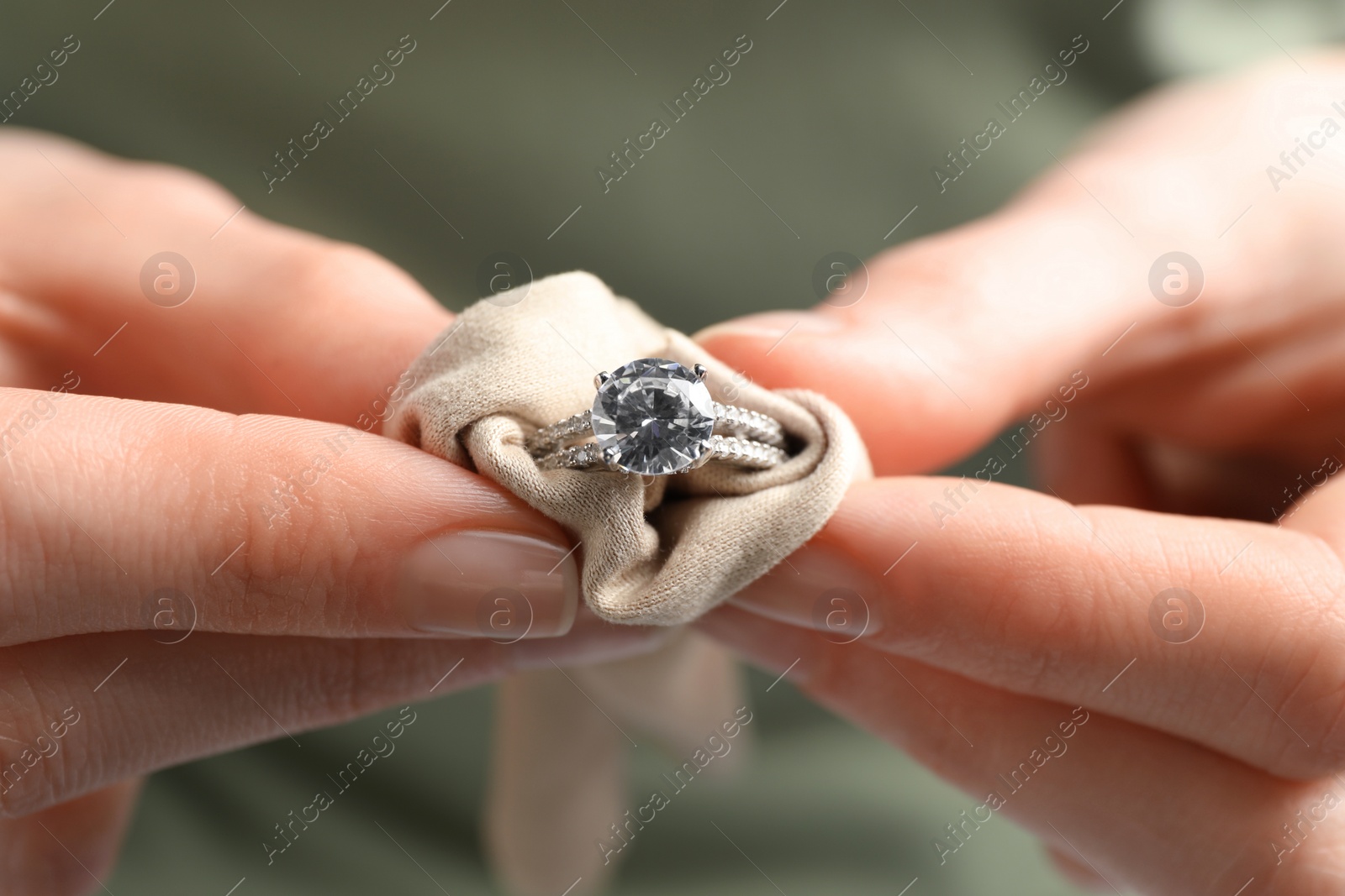 Photo of Jeweler cleaning diamond ring with microfiber cloth, closeup