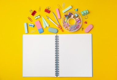 Photo of Flat lay composition with notebook and different school stationery on yellow background. Back to school