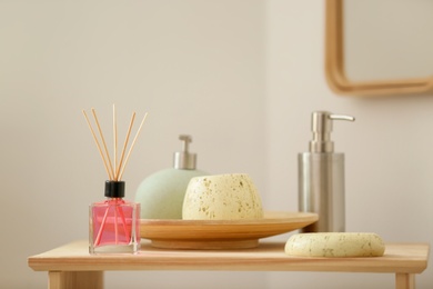 Photo of Aromatic reed air freshener and toiletries on table indoors