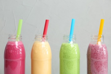 Photo of Bottles with healthy detox smoothies on grey background