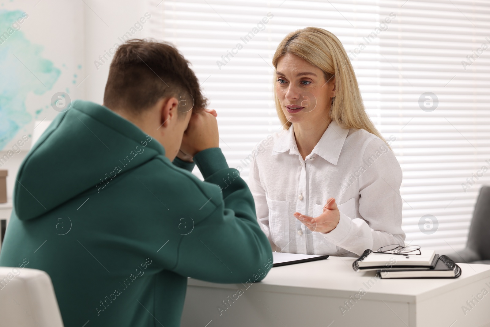 Photo of Psychologist working with teenage boy at table in office