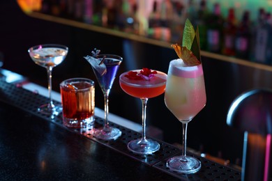 Photo of Different fresh alcoholic cocktails on counter in bar