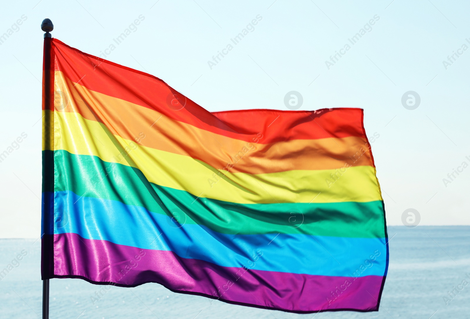 Photo of Rainbow gay flag against blue sky. LGBT concept