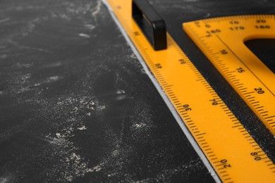 Photo of Ruler and protractor with measuring length and degrees markings on blackboard, closeup. Space for text