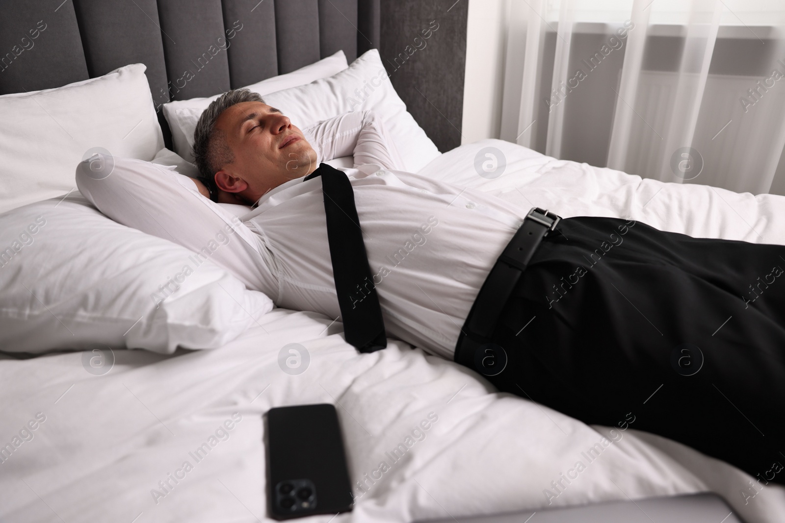 Photo of Businessman in office clothes resting on bed indoors