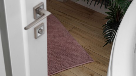 Photo of Soft bath mat near tub on wooden floor in bathroom