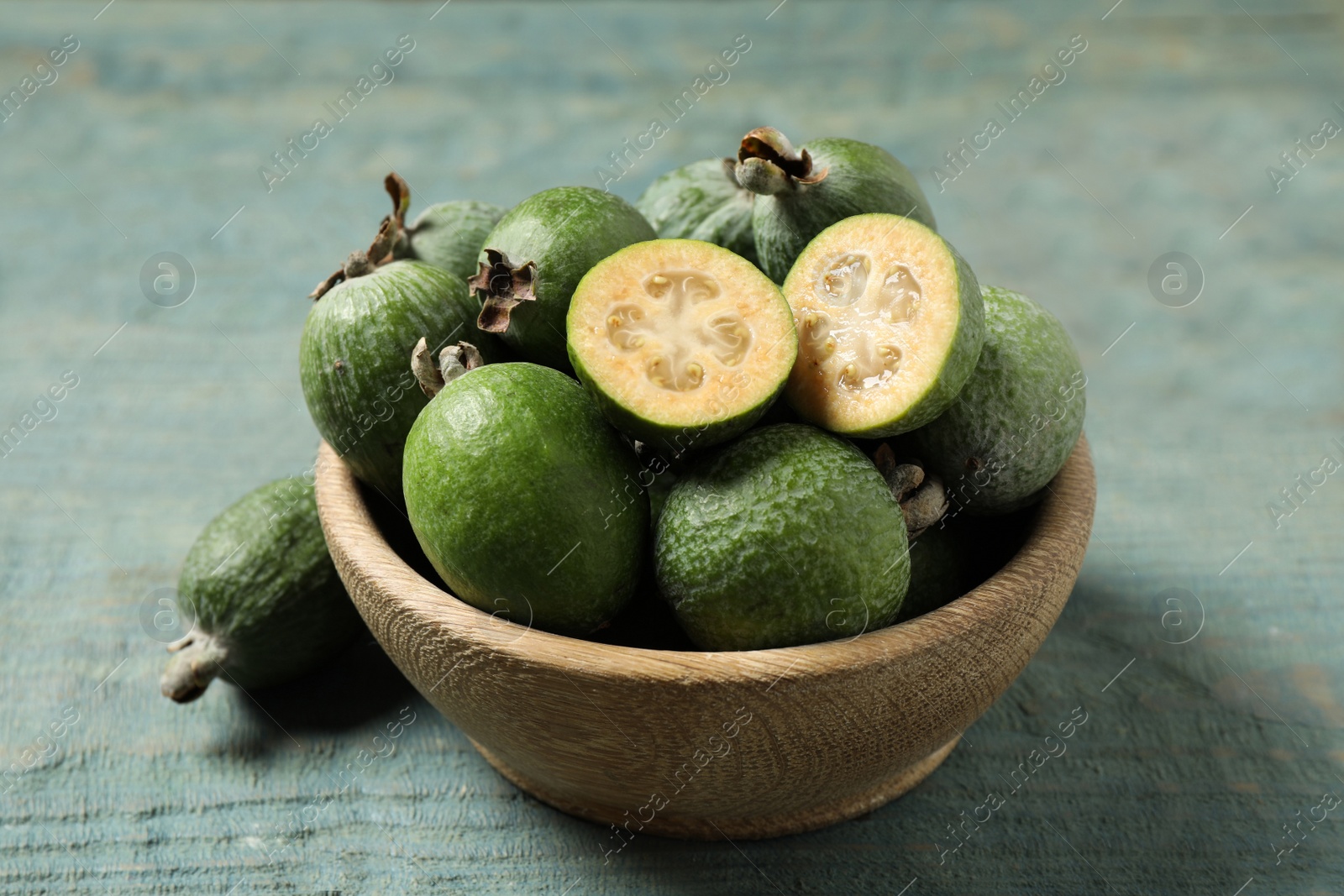 Photo of Fresh green feijoa fruits on blue wooden table, closeup