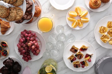 Photo of Variety of snacks on white marble table in buffet style, flat lay