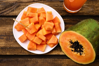 Flat lay composition with fresh papayas and juice on wooden table