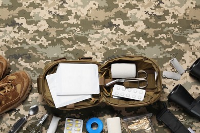 Photo of Flat lay composition with military first aid kit on camouflage fabric. Space for text