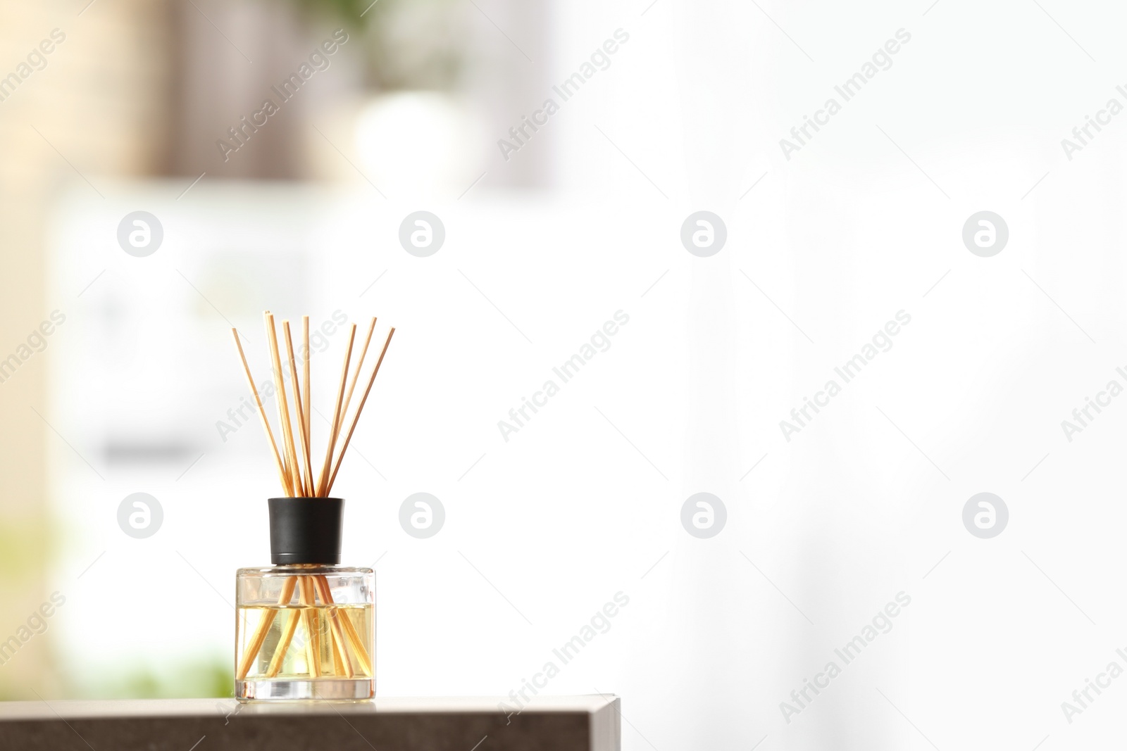 Photo of Aromatic reed air freshener on table against blurred background