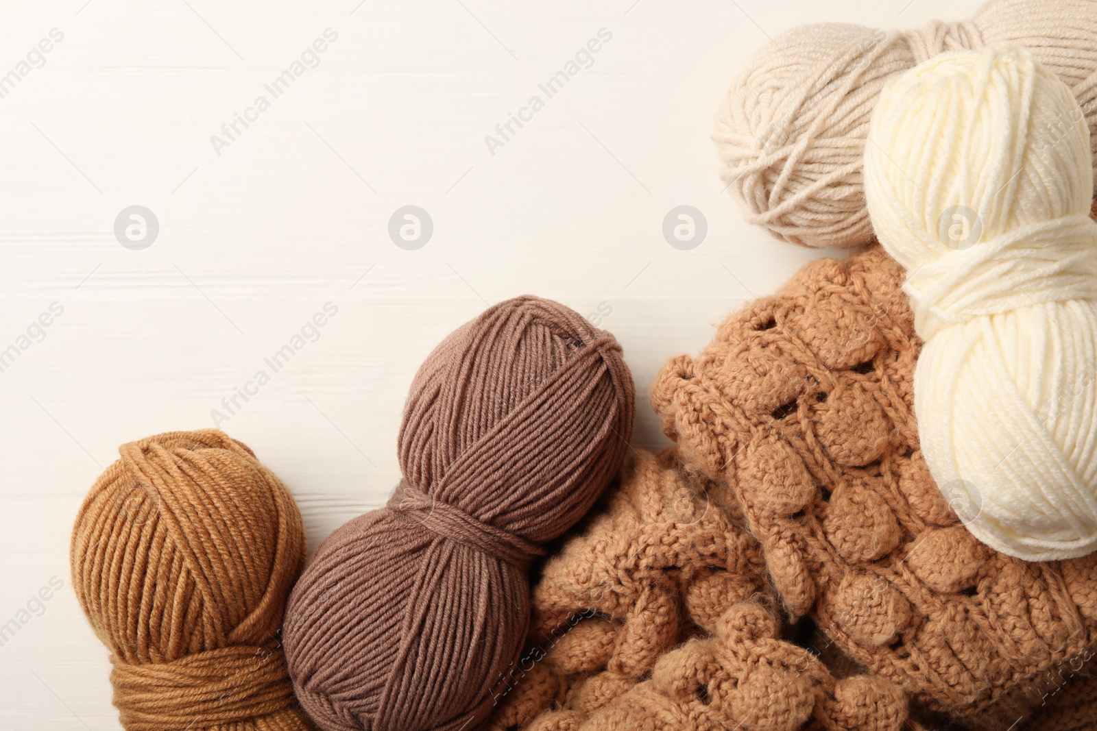 Photo of Woolen yarns and sweater on white wooden background, flat lay