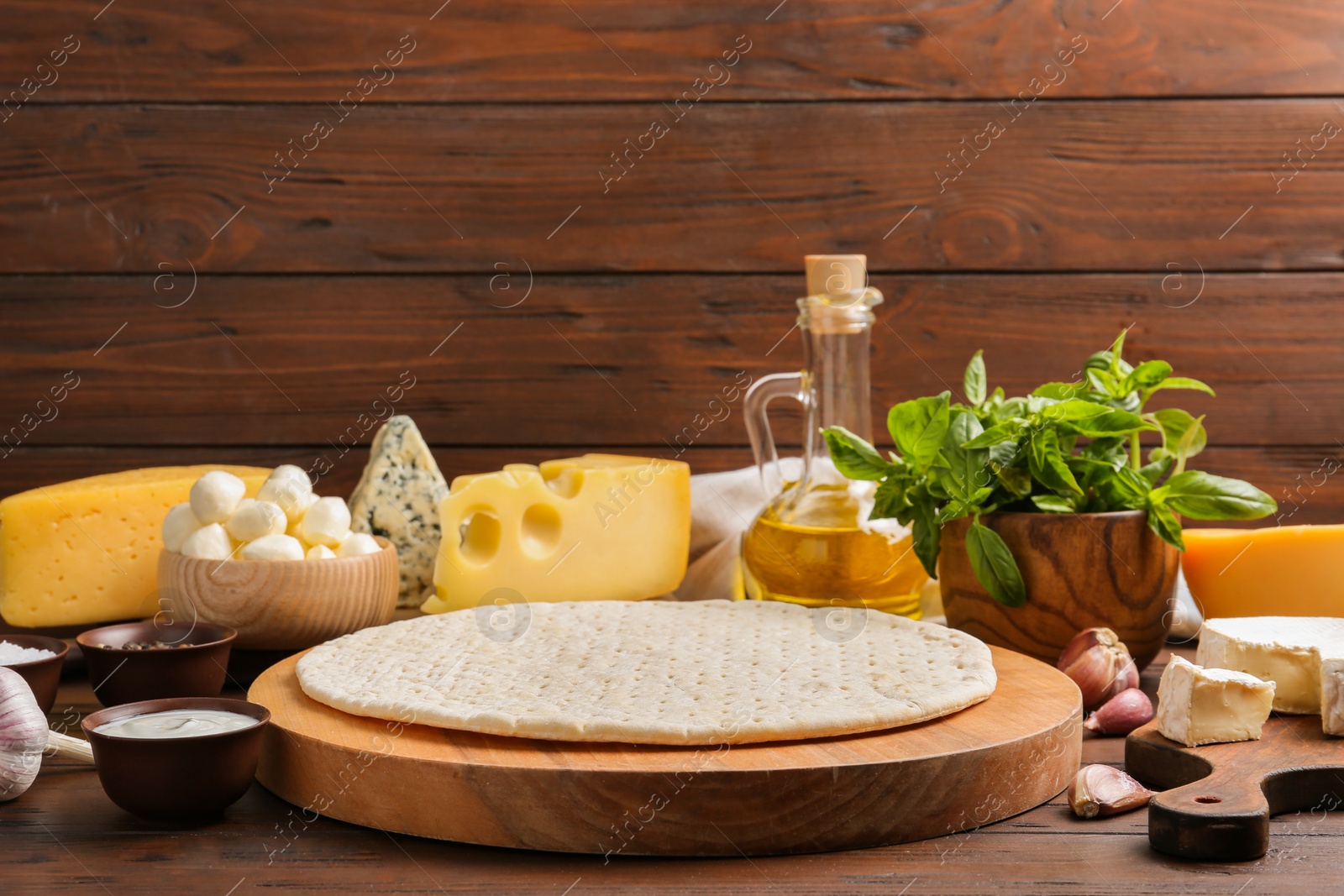 Photo of Pizza crust and fresh ingredients on wooden table