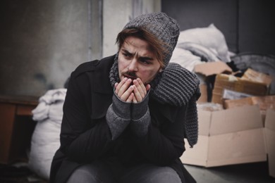 Poor young man sitting near garbage at dump