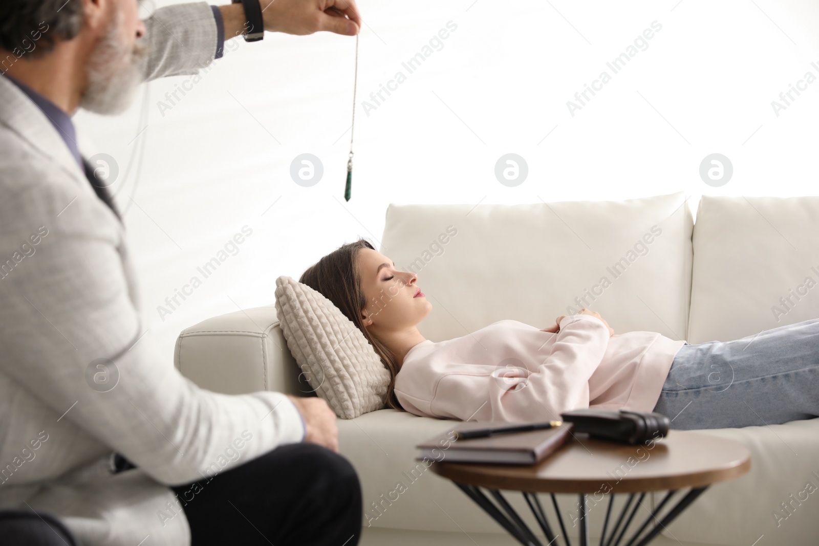 Photo of Psychotherapist using pendulum during hypnotherapy   session in office