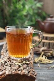 Photo of Aromatic licorice tea in cup and on black wooden table