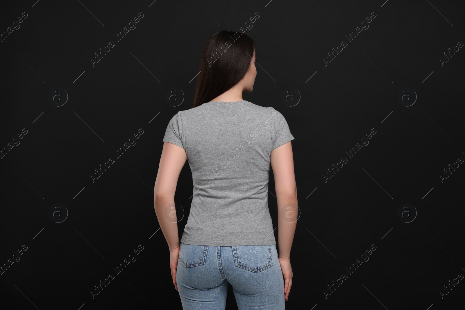 Photo of Woman wearing grey t-shirt on black background, back view