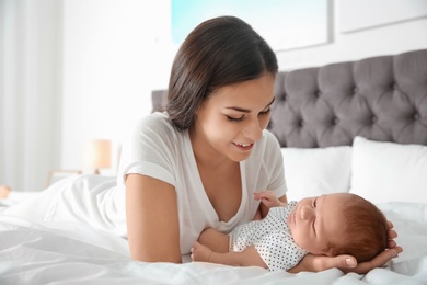 Photo of Young woman with her newborn baby on bed