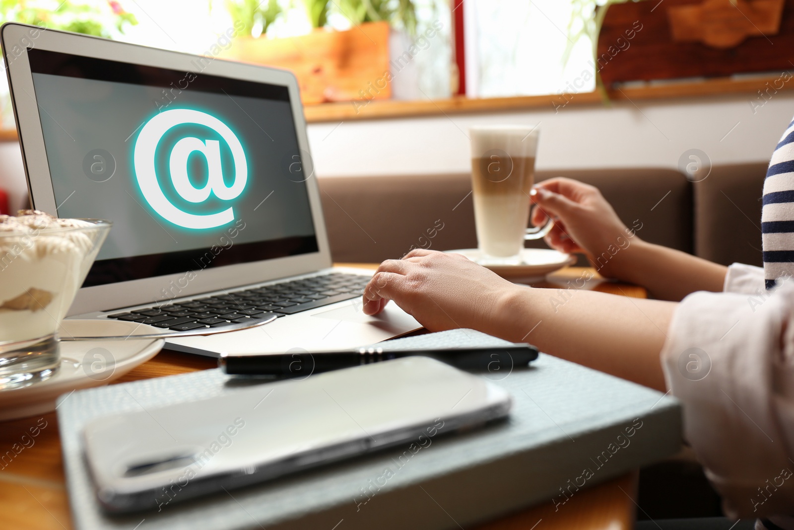 Image of Woman sending email via laptop in cafe, closeup