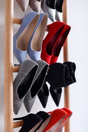 Rack with high heeled shoes on light background