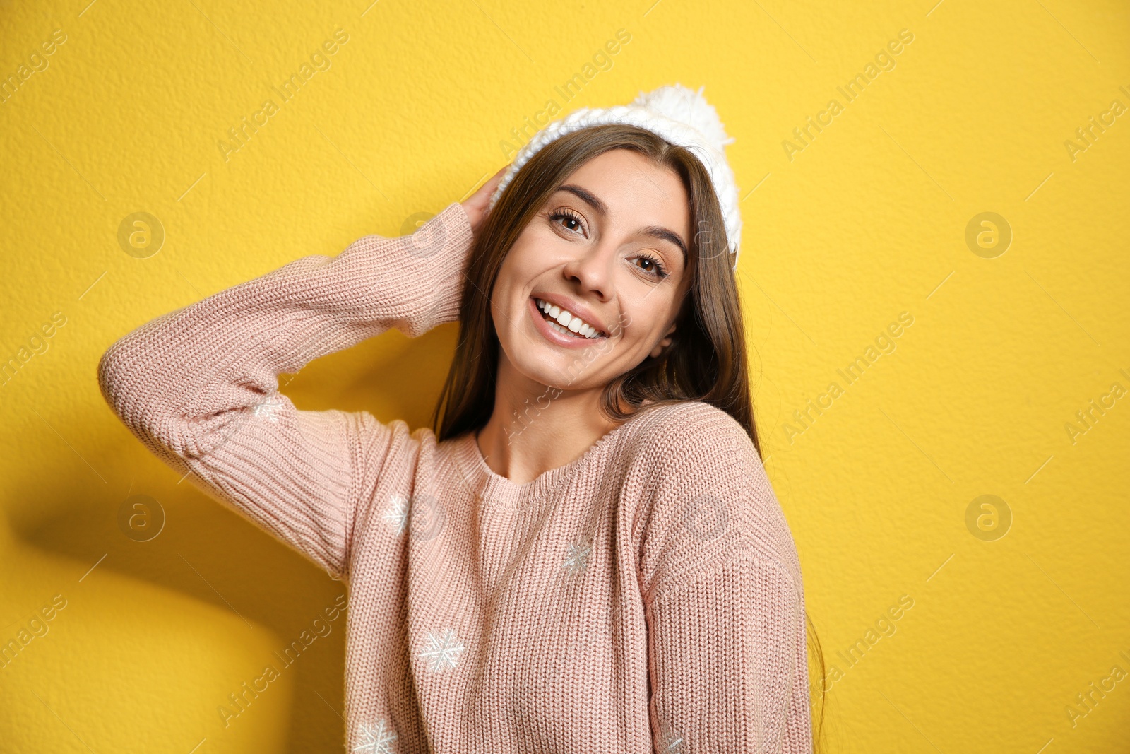 Photo of Beautiful young woman in warm sweater with hat on color background