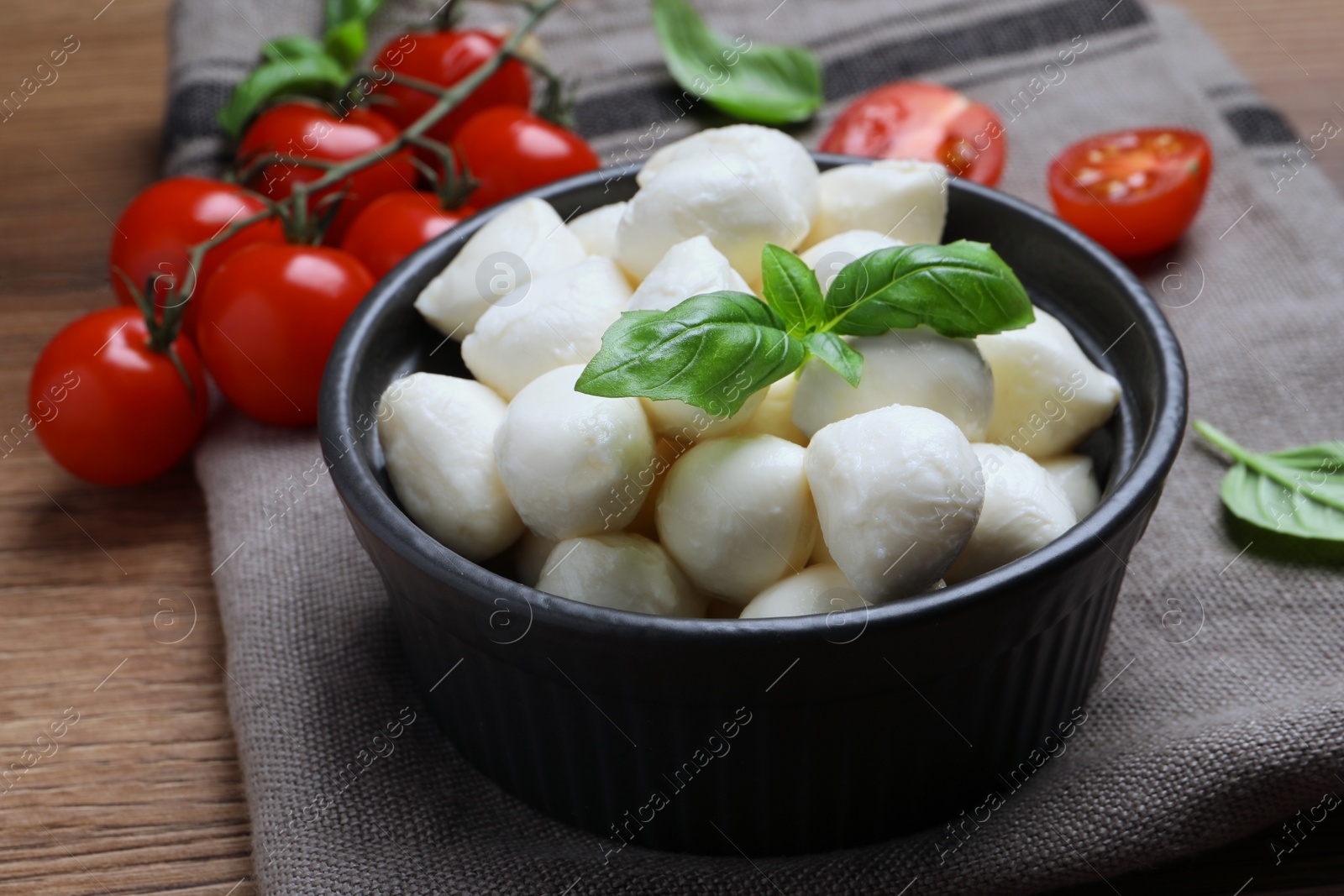 Photo of Delicious mozzarella balls, tomatoes and basil leaves on wooden table