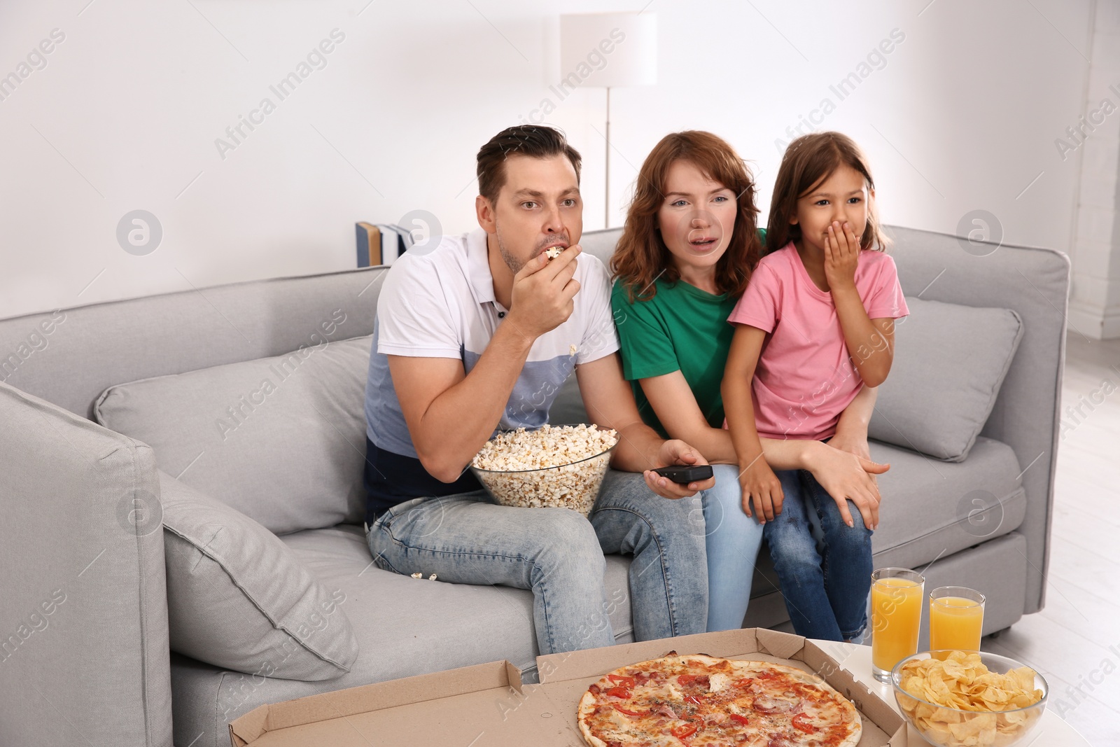 Photo of Family watching TV with popcorn in room