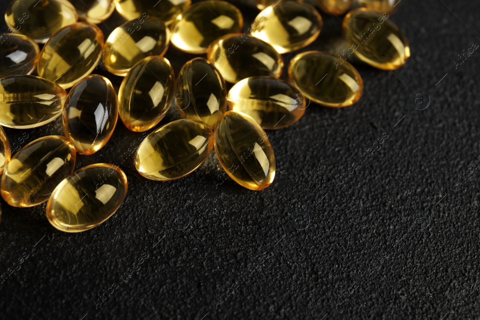 Photo of Cod liver oil pills and space for text on dark background, closeup