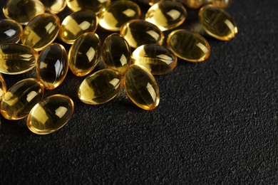 Cod liver oil pills and space for text on dark background, closeup
