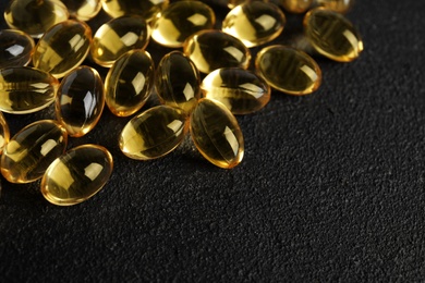 Photo of Cod liver oil pills and space for text on dark background, closeup