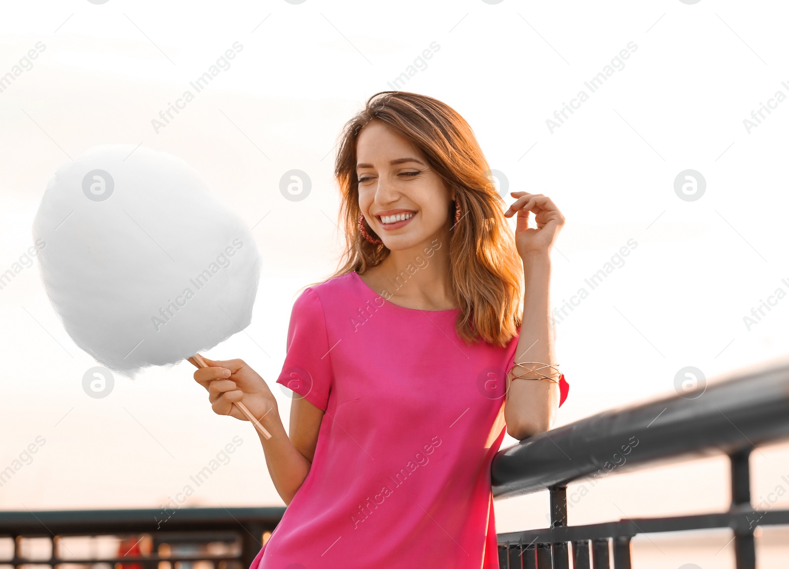 Photo of Happy young woman with cotton candy on waterfront