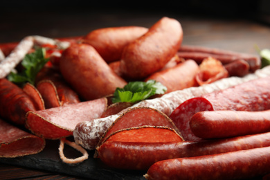 Different tasty sausages on wooden table, closeup