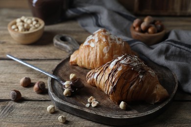 Delicious croissants with chocolate and nuts on wooden table